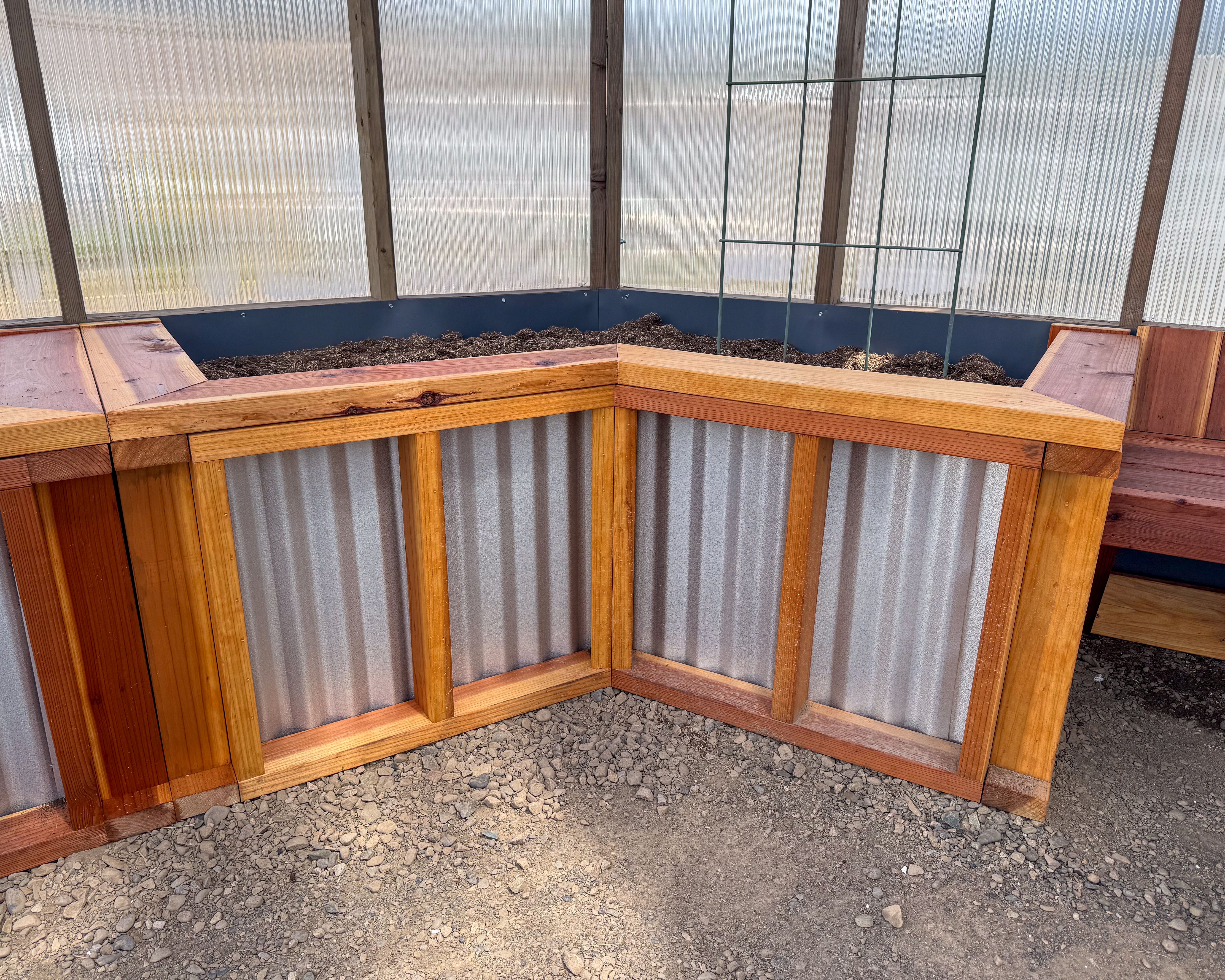Redwood trimmed corrugated raised garden bed filled with soil