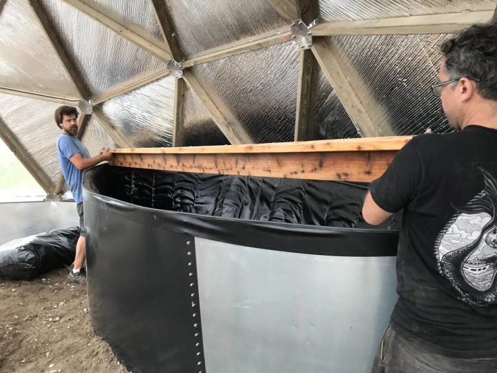Volunteers installing pond in geodesic dome greenhouse