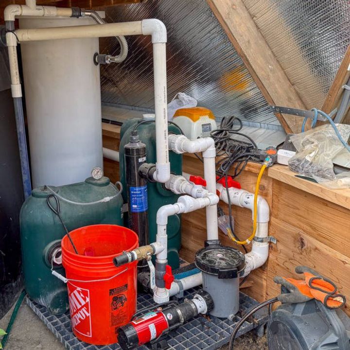 Green polybead water filters with white pvc tubing and a bright orange bucket