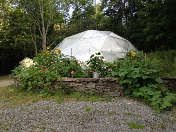 raised beds made of stone walls around a geodesic greenhouse