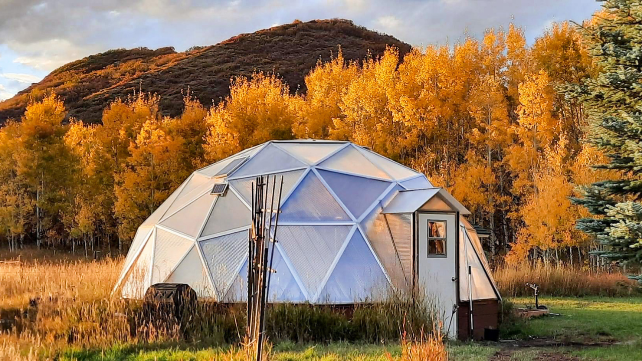 22′ Growing Dome geodesic greenhouse exterior surrounded by golden autumn trees.