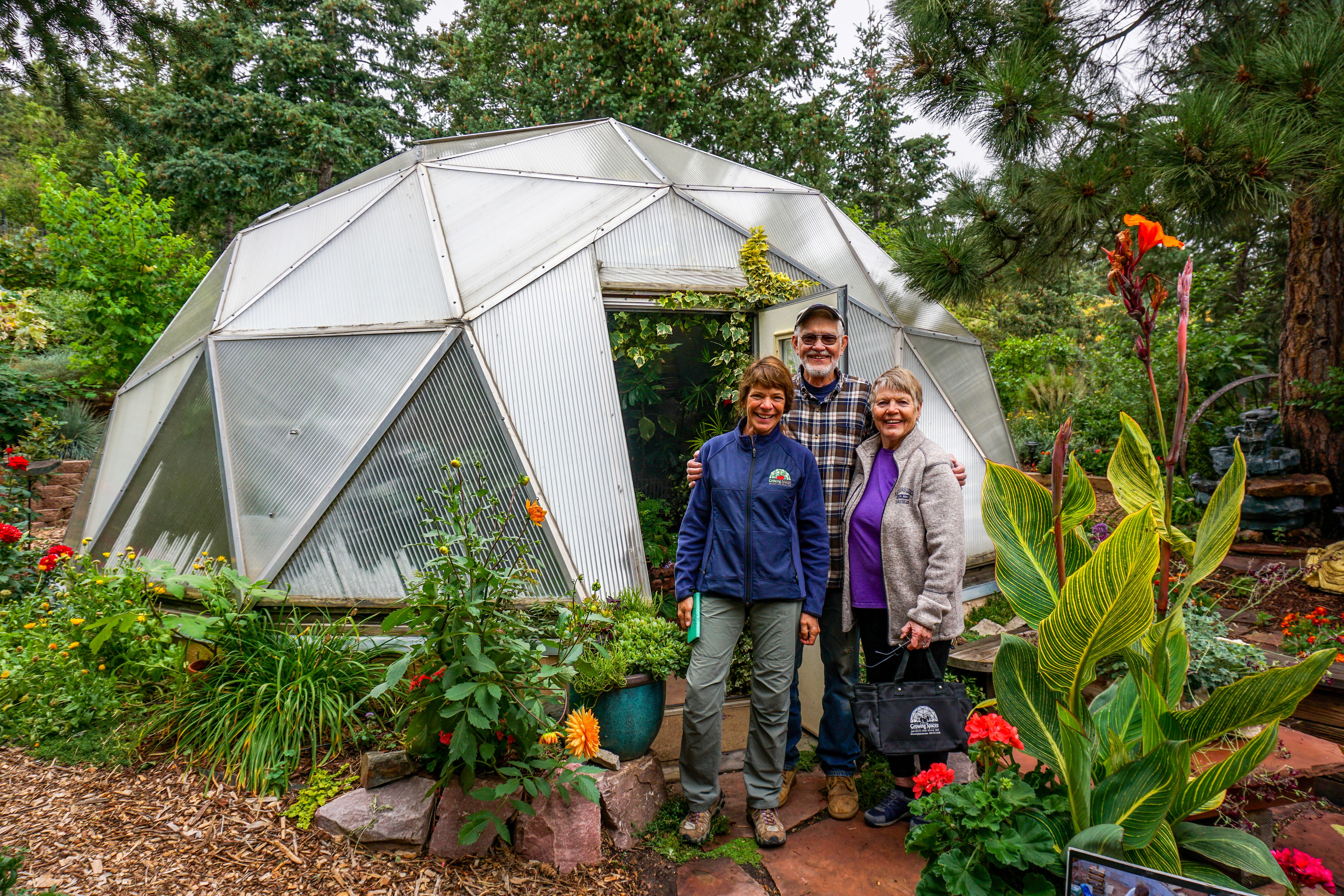 group of people standing outside of a small growing dome greenhouse