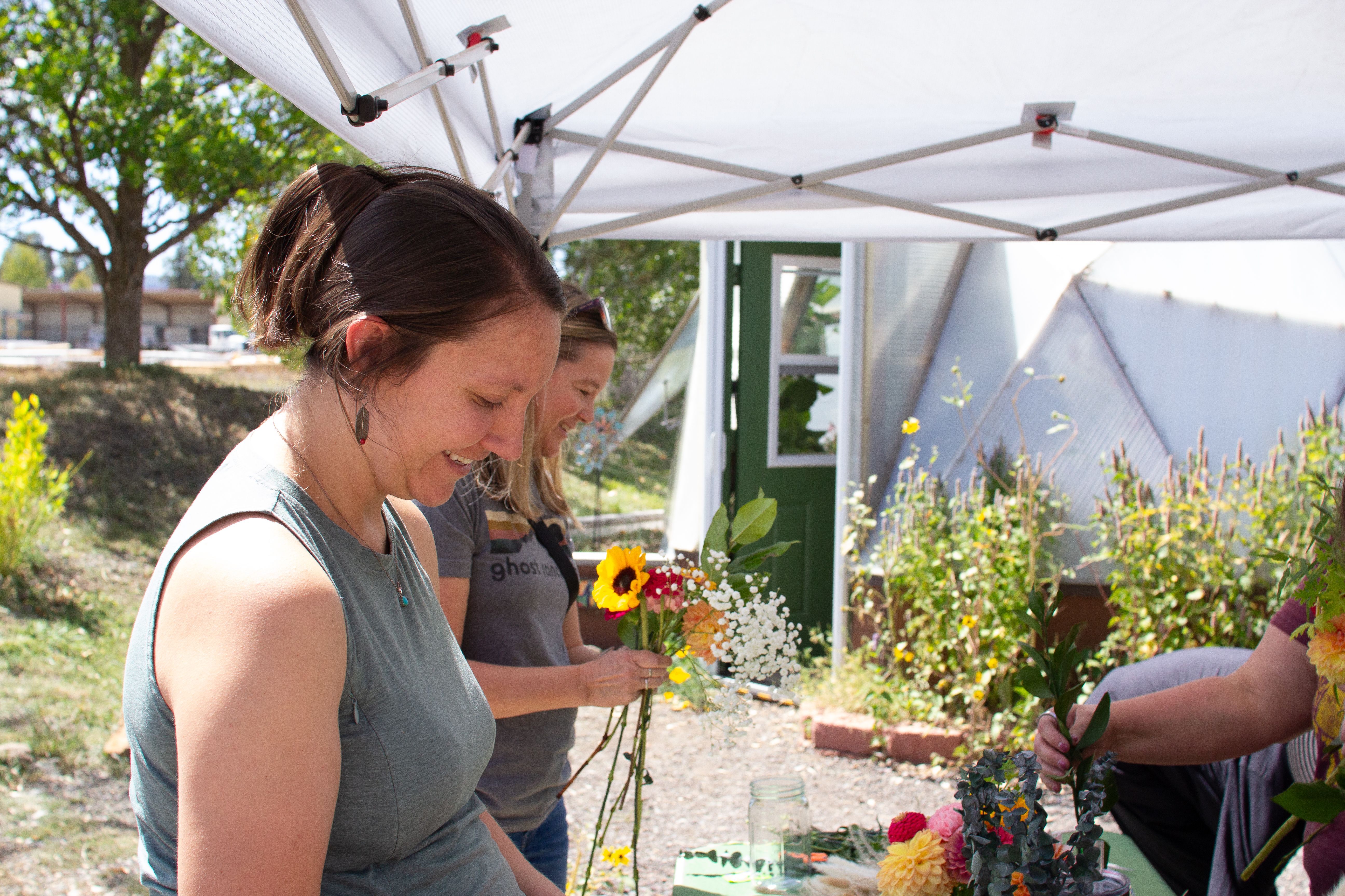 Two women smiling making bouquets outside a Growing Dome greenhouse