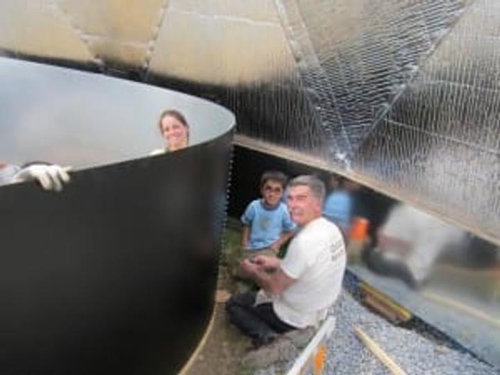 People constructing an above ground greenhouse pond
