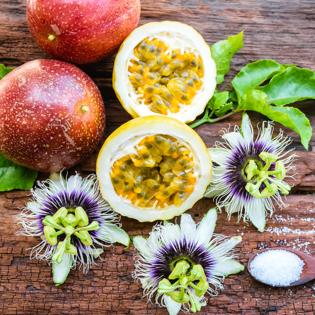 harvested passion fruit and flowers with a fruit cut in half to expose the pulp and seeds