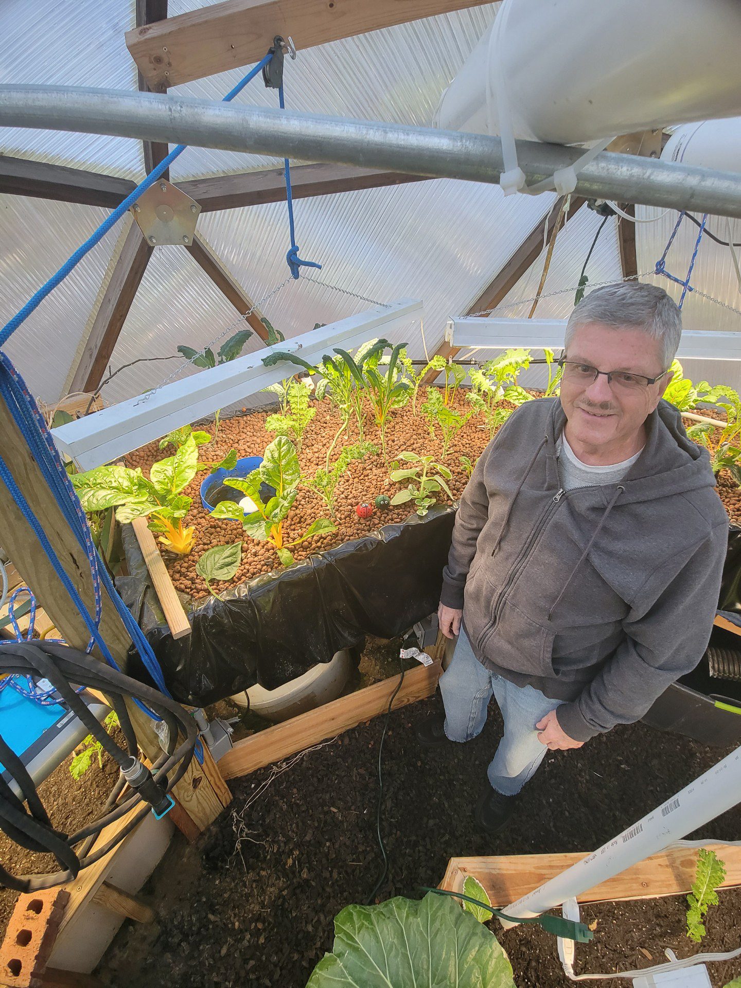 Grower standing beside a deep-water culture bed inside a Growing Dome in Clayton, North Carolina