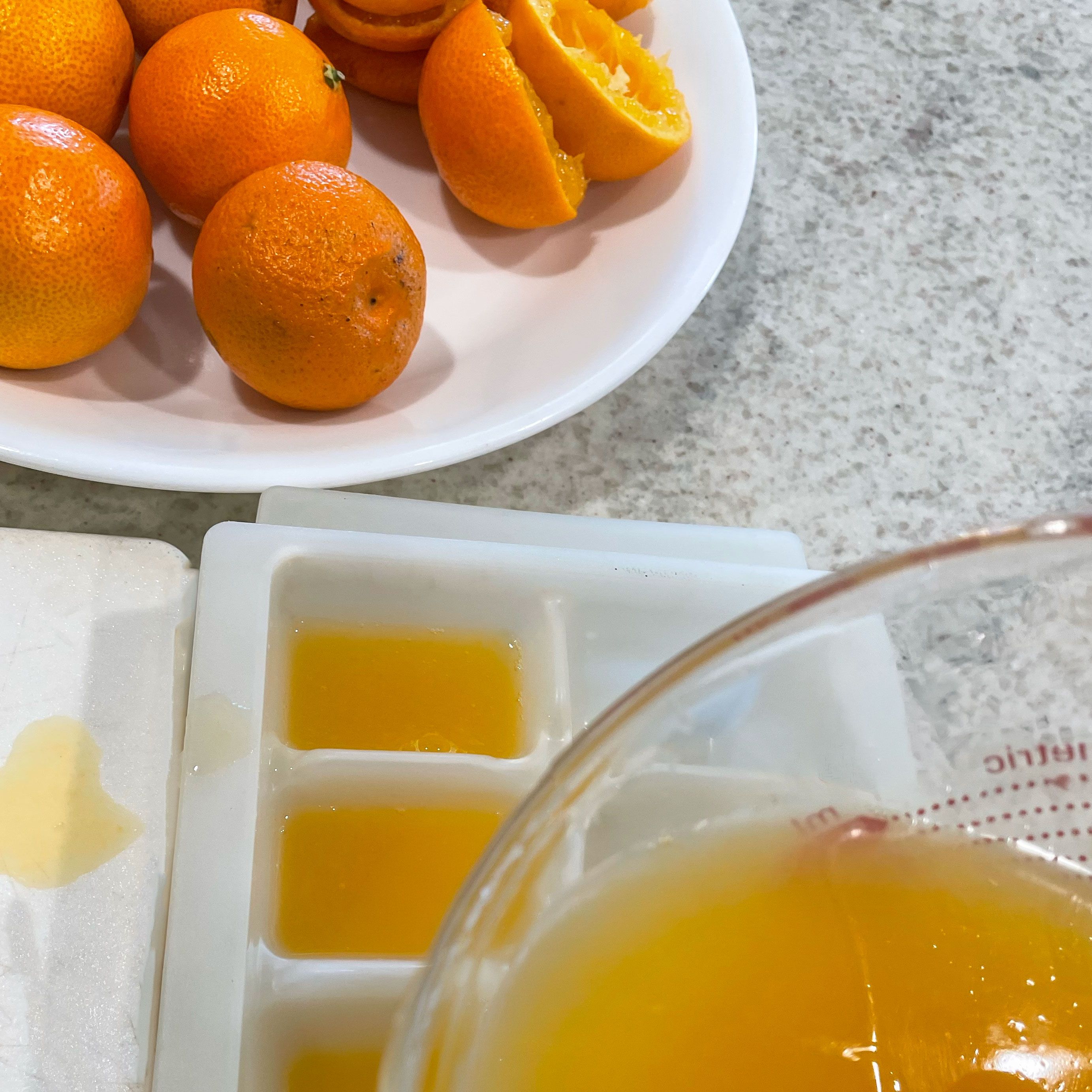 plate of mandarin oranges and pouring juice into an ice cube tray