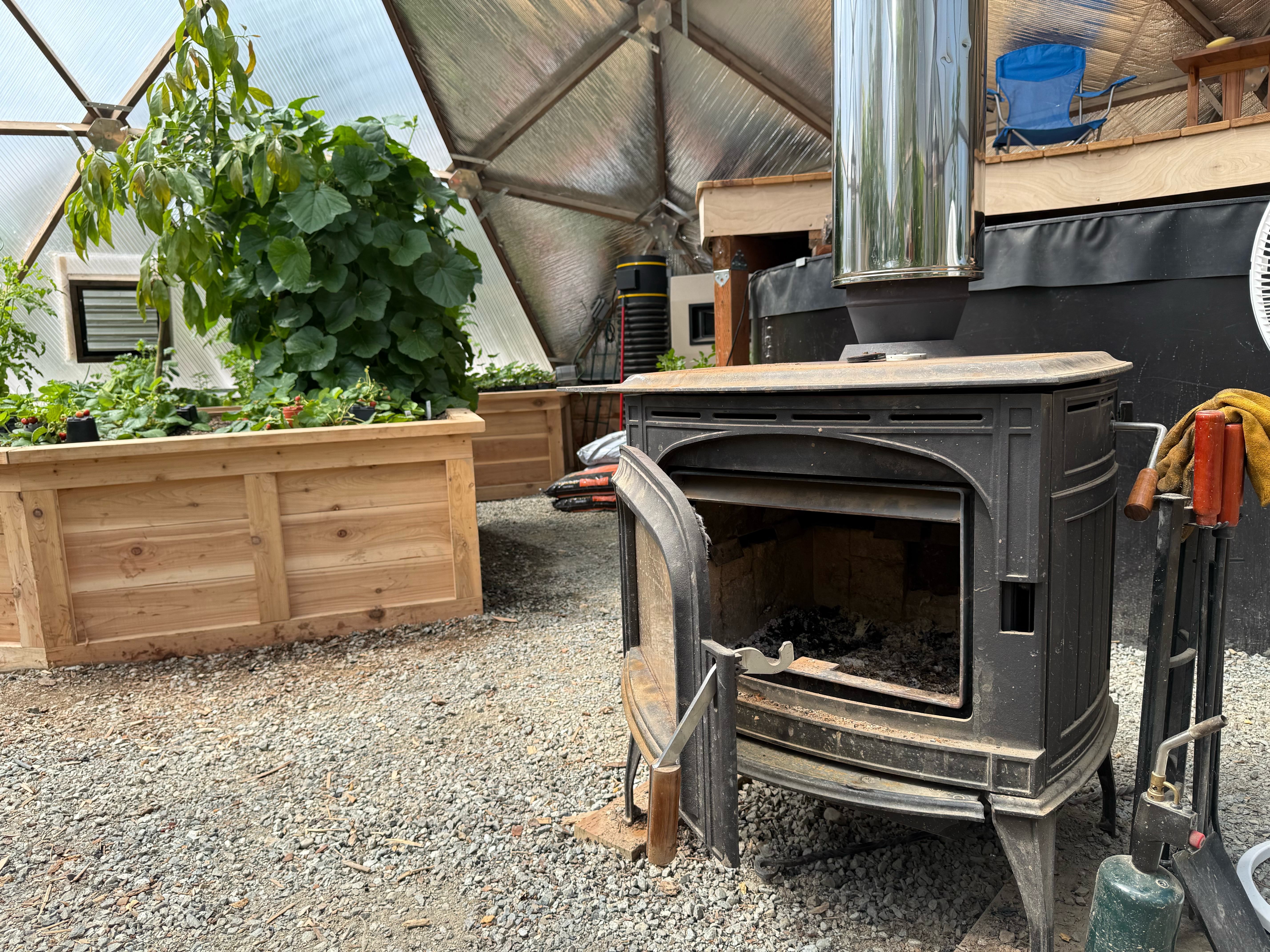 Wood stove with door open in a geodesic greenhouse
