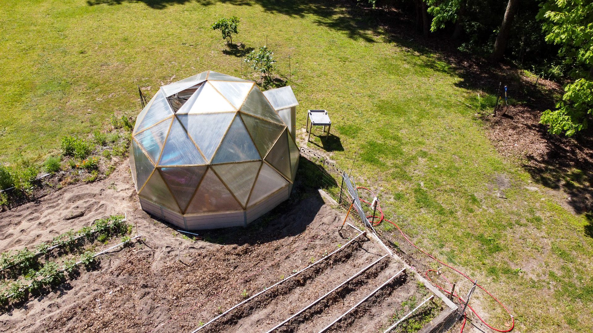 An 18-foot Growing Dome beside an outdoor garden in Clayton, North Carolina