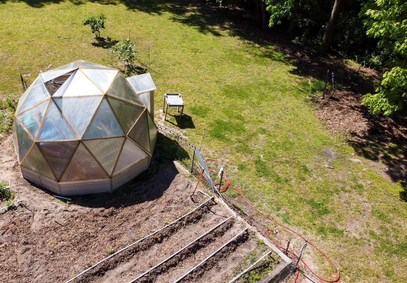 An 18-foot Growing Dome beside an outdoor garden in Clayton, North Carolina