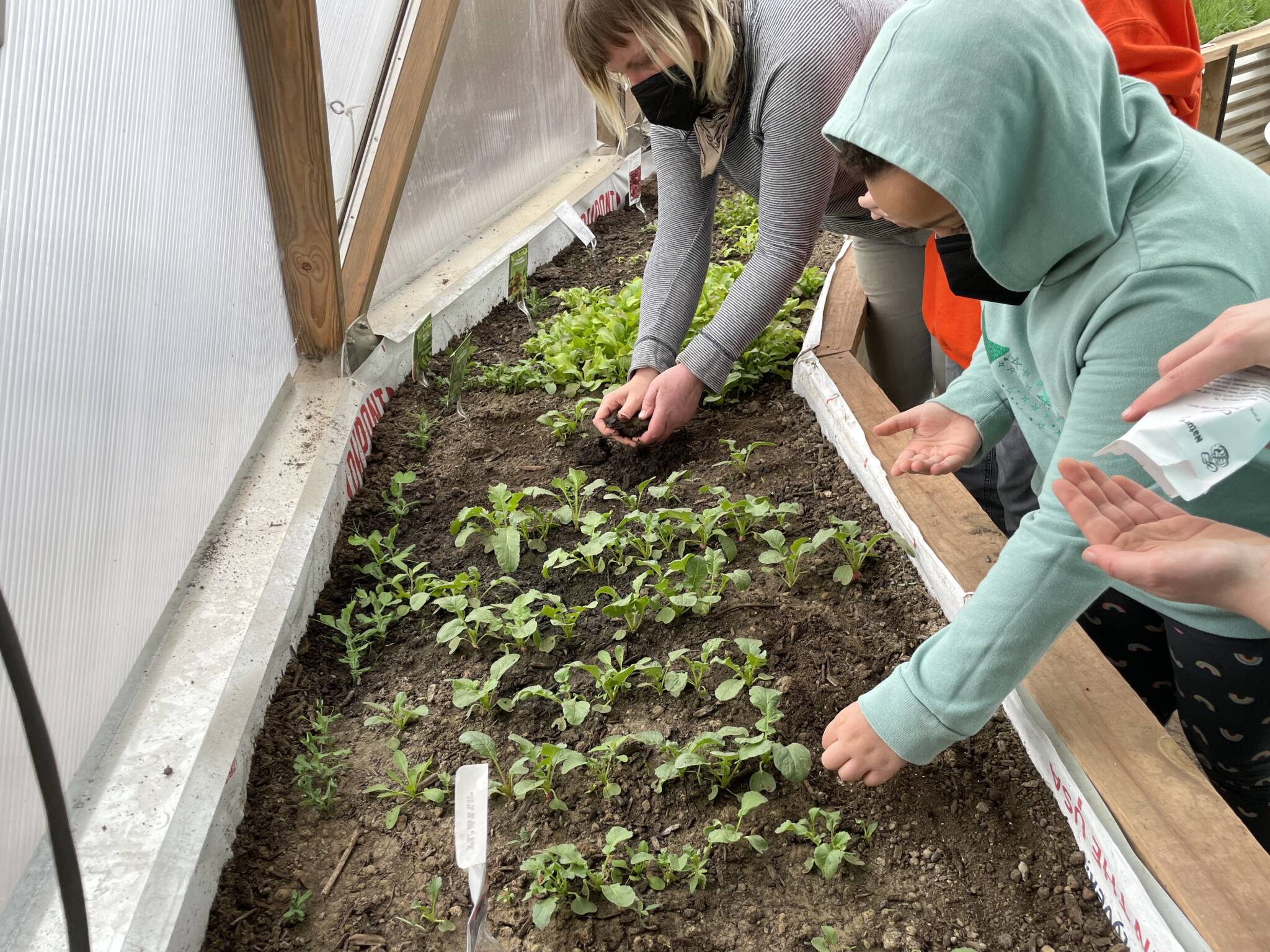Child and parent planting seeds in a Growing Dome greenhouse