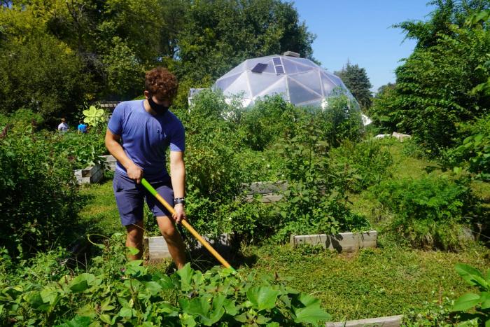 Man tending to an urban garden with a Growing Dome in the background