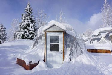 small deep winter greenhouse covered in snow