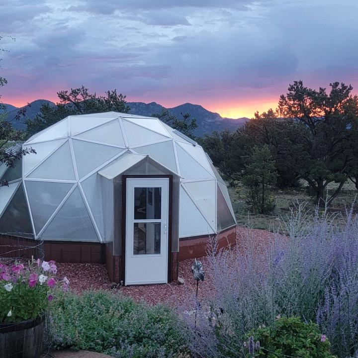 This image has a purple tone with the clouds, mountains and sunset behind a Growing Dome and Russian Sage in the foreground.