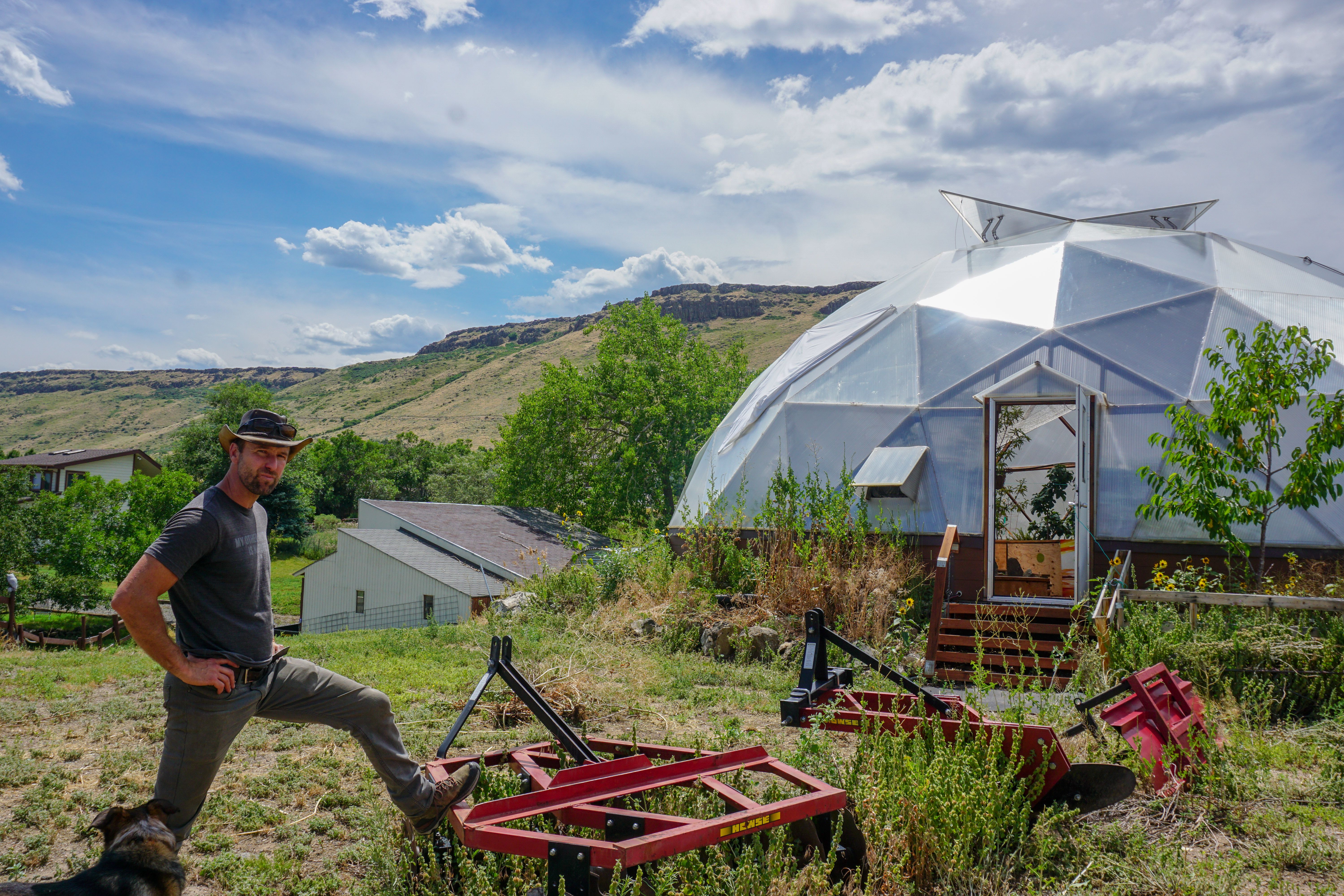 Man in a cowboy hat standing outside a dome greenhouse