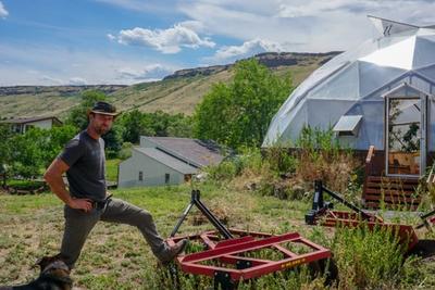 Man in a cowboy hat standing outside a dome greenhouse