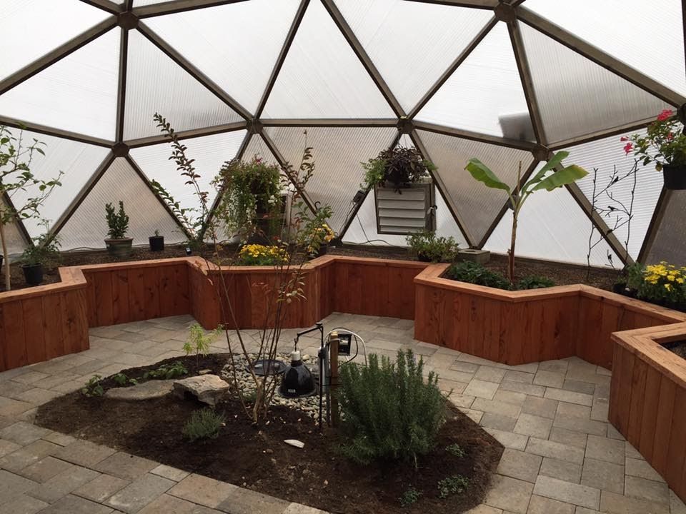 sunken center bed surrounded by paver pathway and vertical wooden perimeter beds in a geodesic dome greenhouse