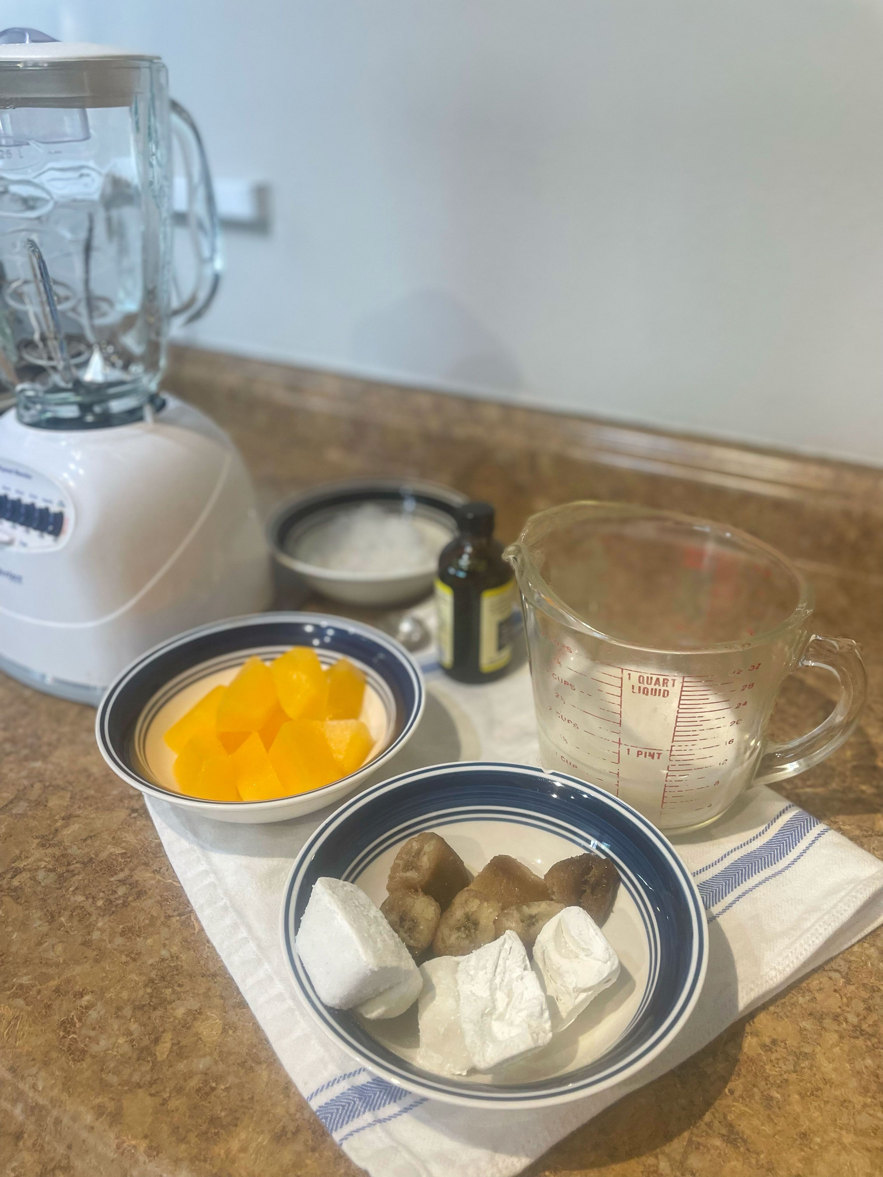 ingredients prepped for vegan orange julius almond milk coconut and mandarin cubes frozen banana vanilla