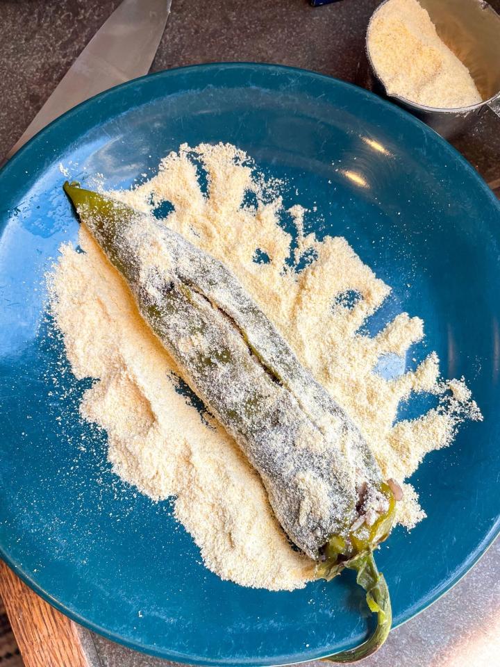 stuffed green chile on a plate sprinkled with masa corn meal