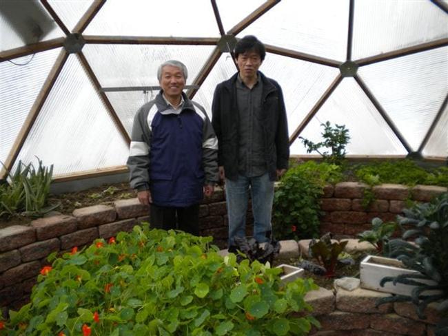 Two gardeners standing among winter greens inside a Pennsylvania Growing Dome