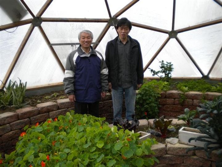 Two men standing inside a Growing Dome greenhouse