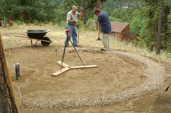 Two people leveling a gravel ring foundation for a Growing Dome