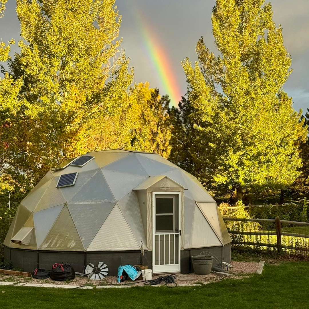 Growing Dome greenhouse under a rainbow surrounded by golden trees in fall
