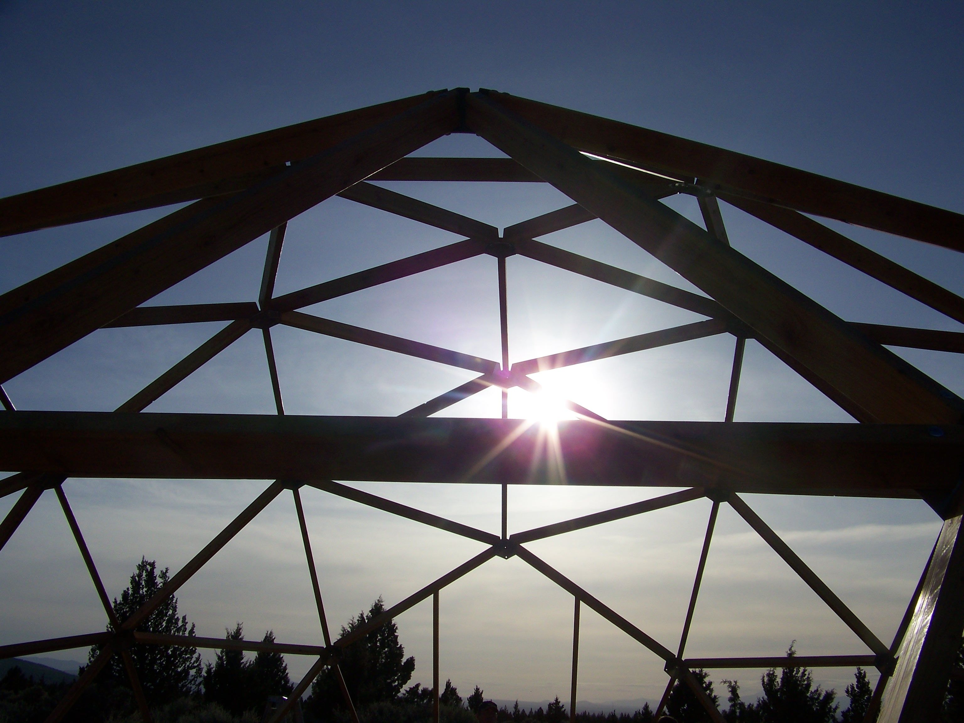 Backlit structural framework of a Growing Dome greenhouse under construction.
