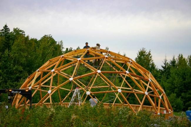 wooden frame of a geodesic dome greenhouse being errected