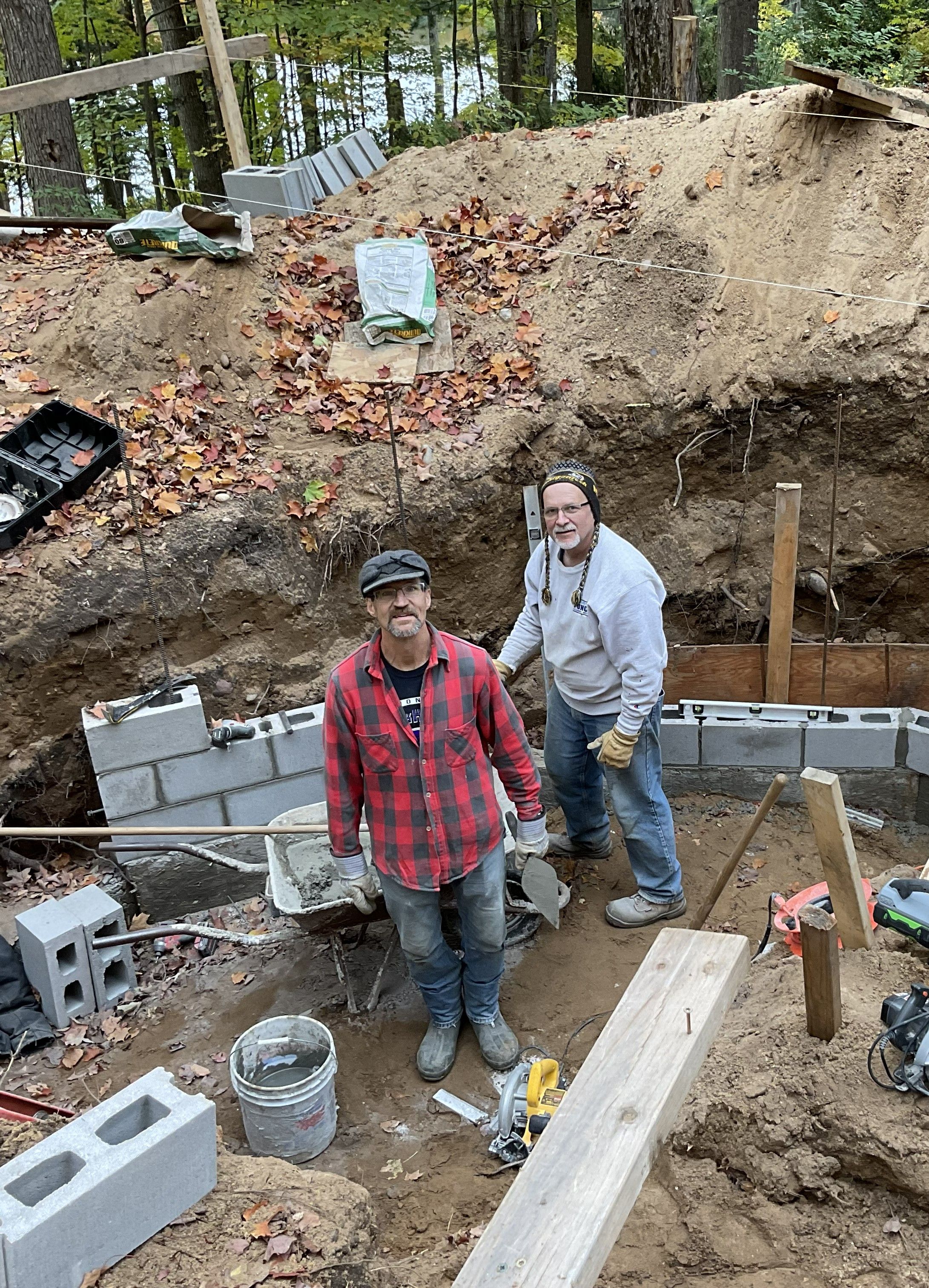 Two people building a custom block basement beneath a Growing Dome in Northern Michigan