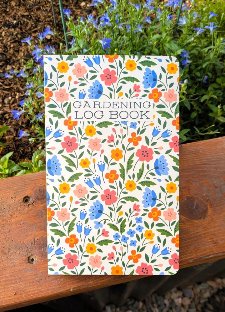 garden journal on a raised bed rail with lobelia blooming in the background