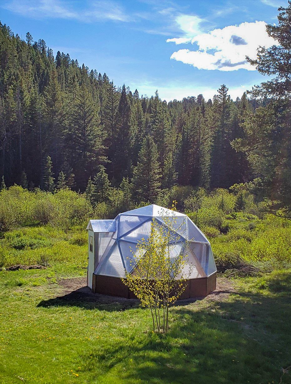 15 foot diameter growing dome in a meadow surrounded by tall evergreens