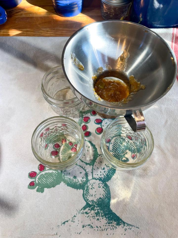 using a wide mouth funnel to fill jars with fig jam