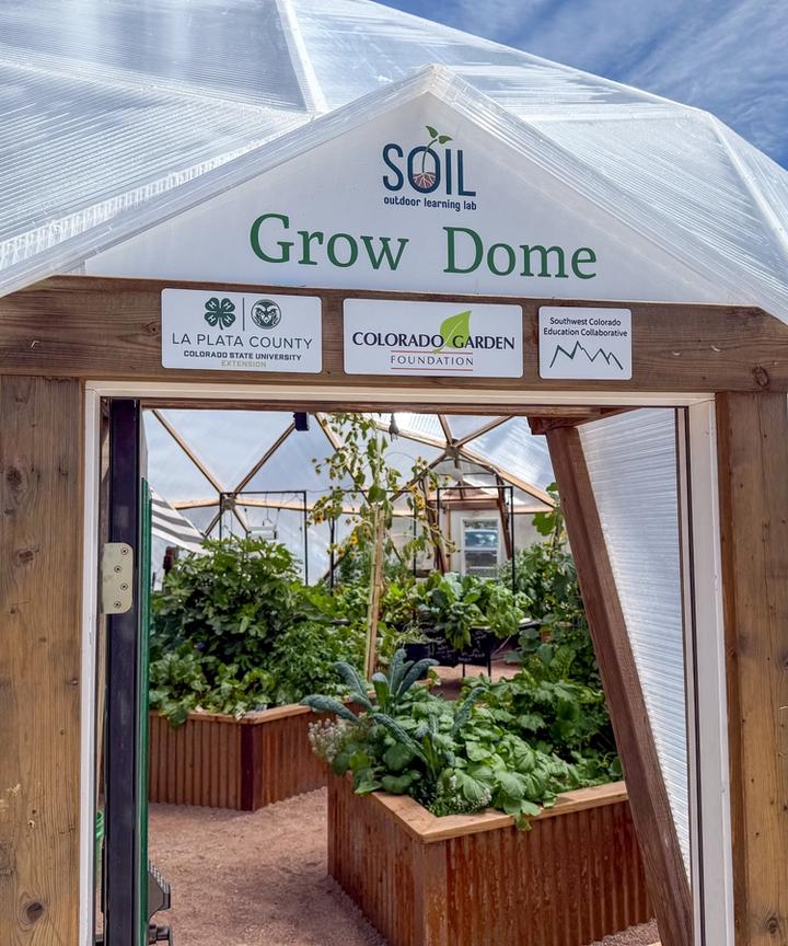 Growing Dome doorway with three donor signs above the door and lush green plants inside
