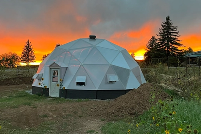 33 foot growing dome greenhouse with a vibrant orange sunset and small sunflowers
