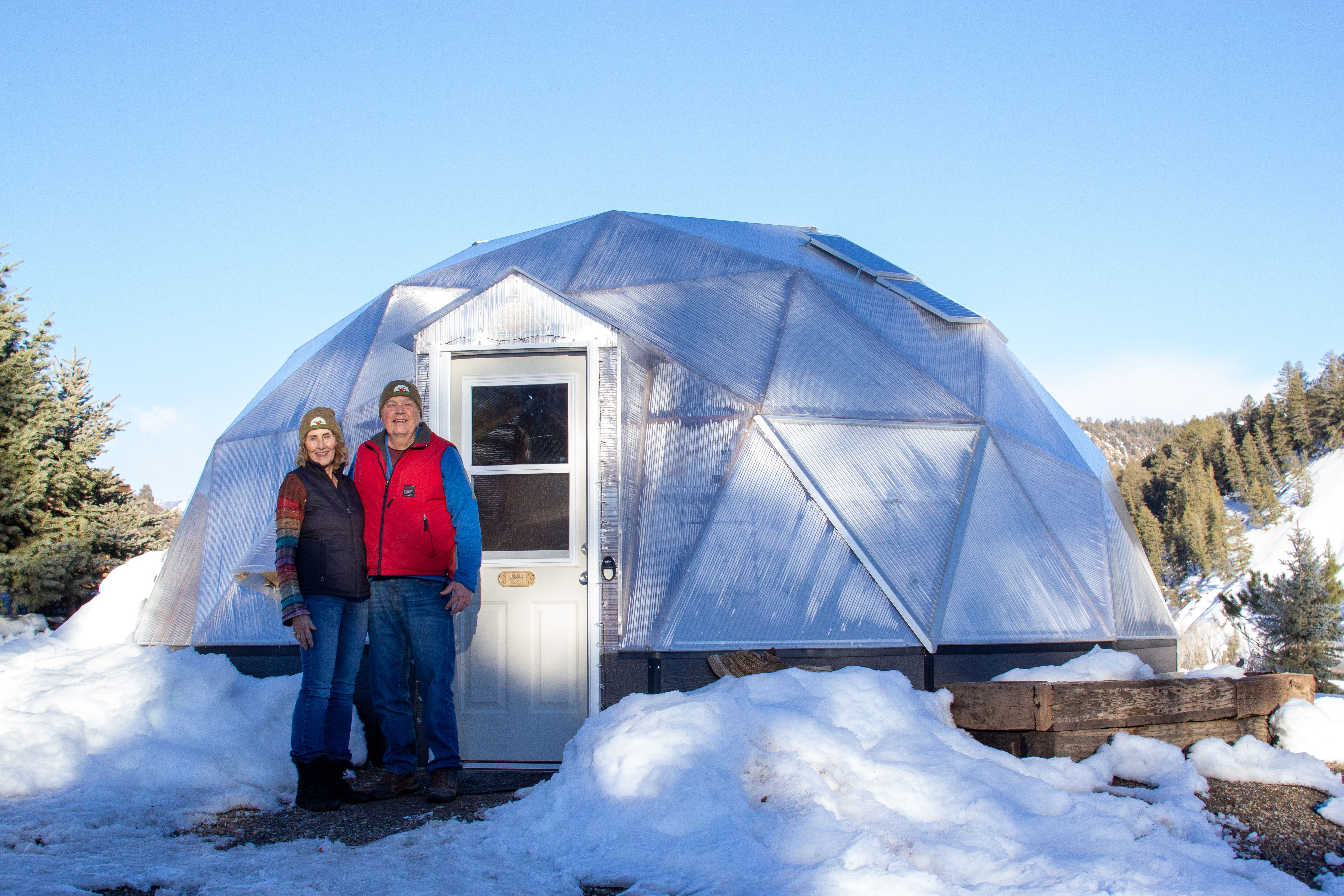 Couple standing outside their Growing Dome with snow on the ground