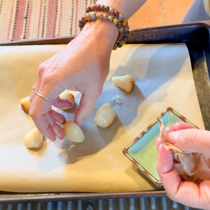 peeling garlic cloves and laying them on a baking sheet with wax paper to be frozen