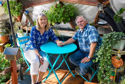 couple sits at a coffee table in their growing dome greenhouse