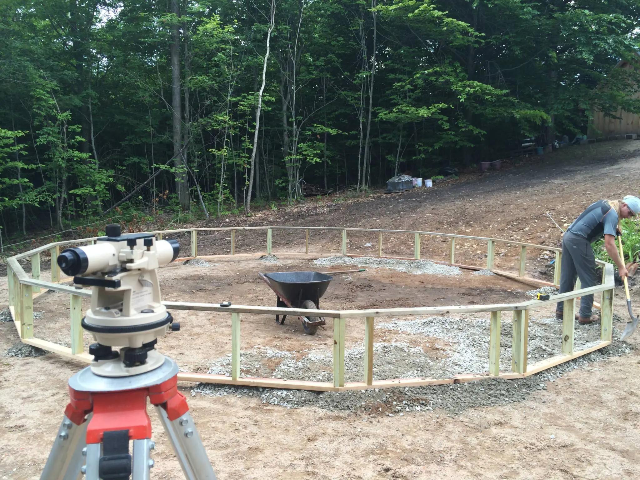 someone scooping gravel under wood frame of the greenhouse foundation wall