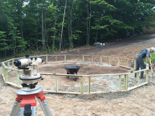 someone scooping gravel under wood frame of the greenhouse foundation wall