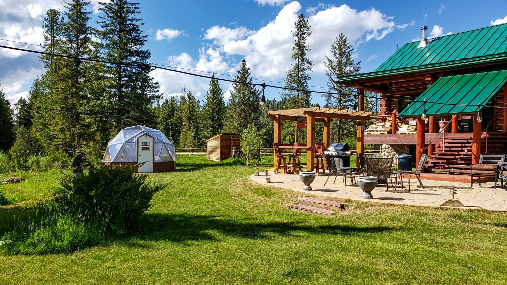 15' growing dome greenhouse in a yard next to the house with a large patio