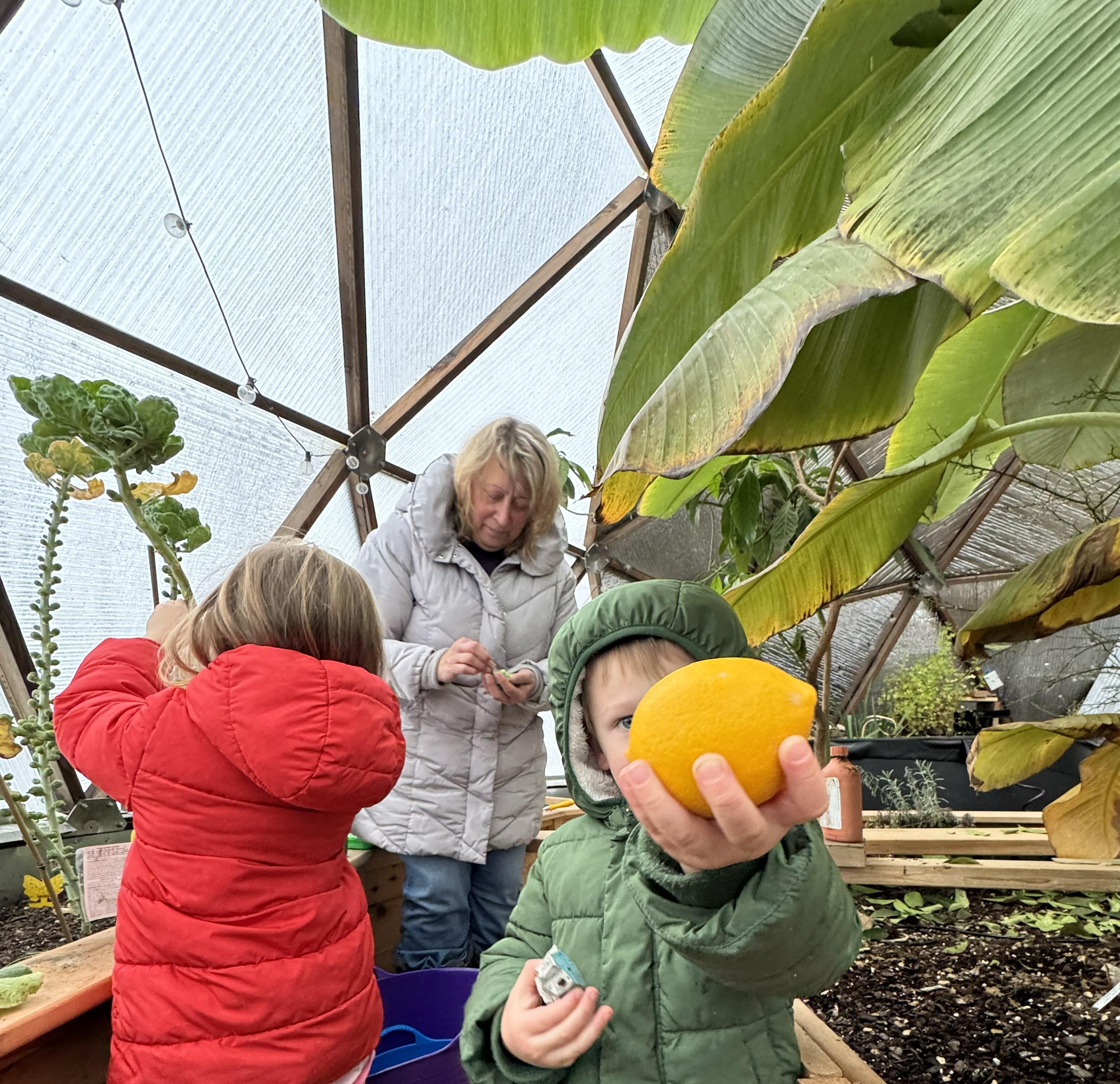A family harvesting produce inside a Northern Michigan Growing Dome