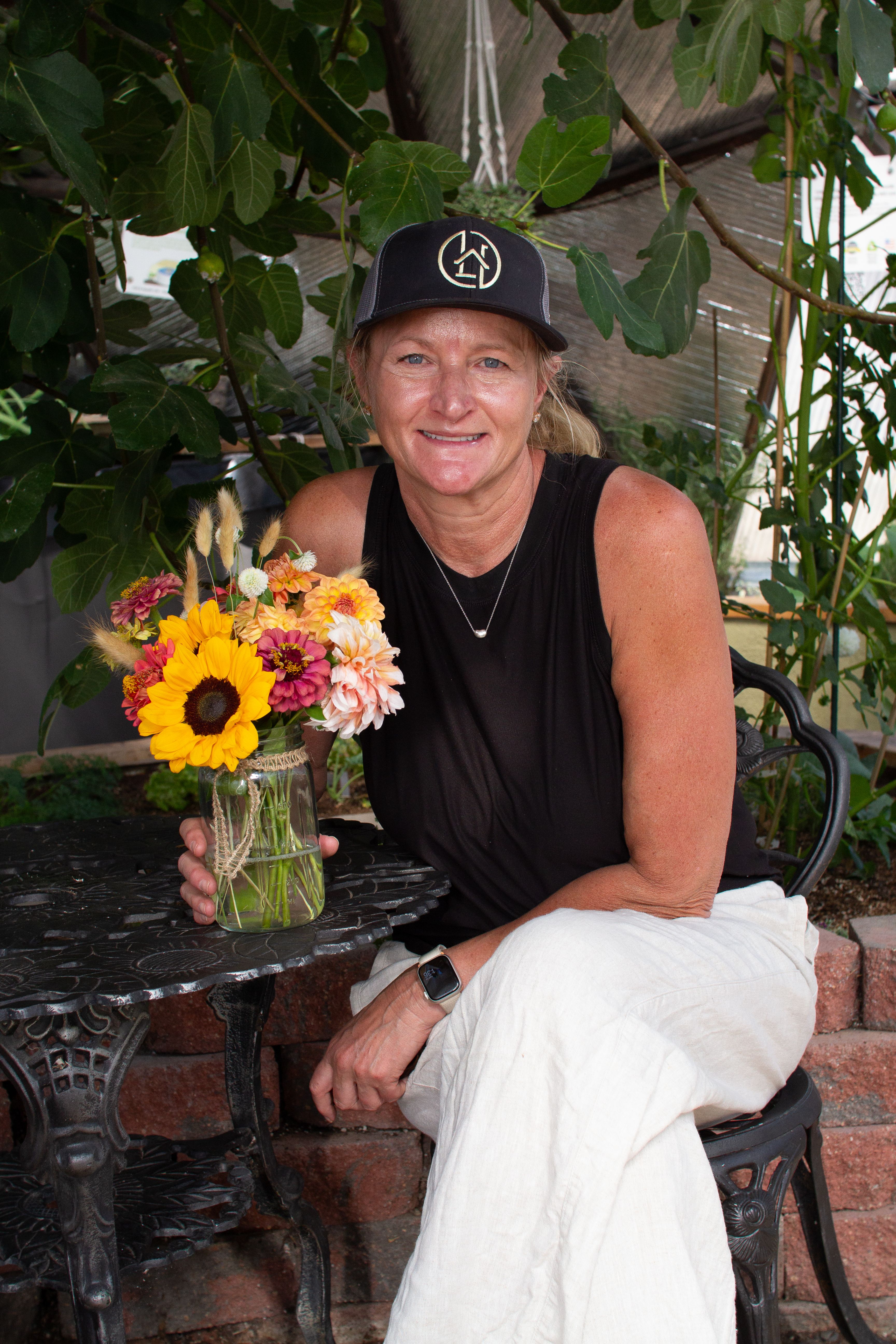 Woman wearing a black hat posing for a photo with her bouquet
