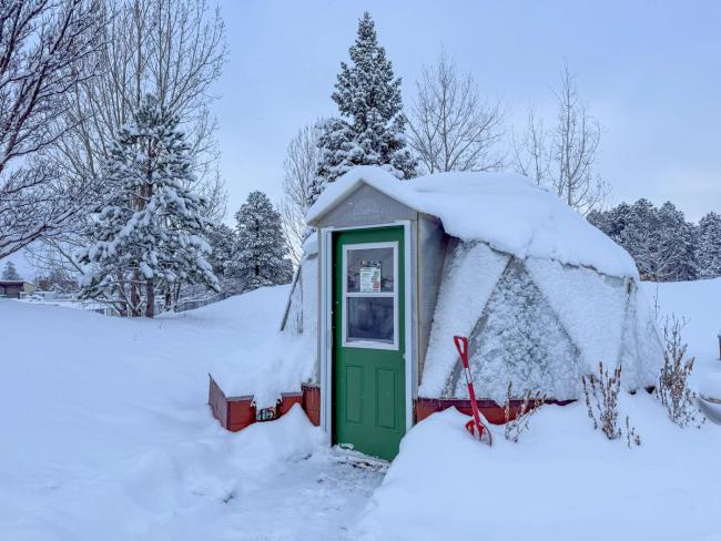 15' Growing Dome with green door covered in a blanket of snow