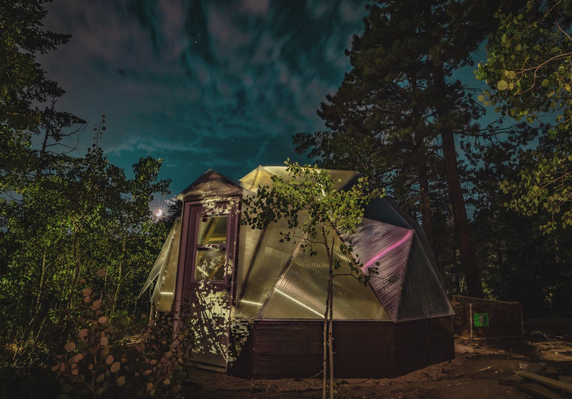 photo of a dome greenhouse at night with light reflecting off the polycarbonate