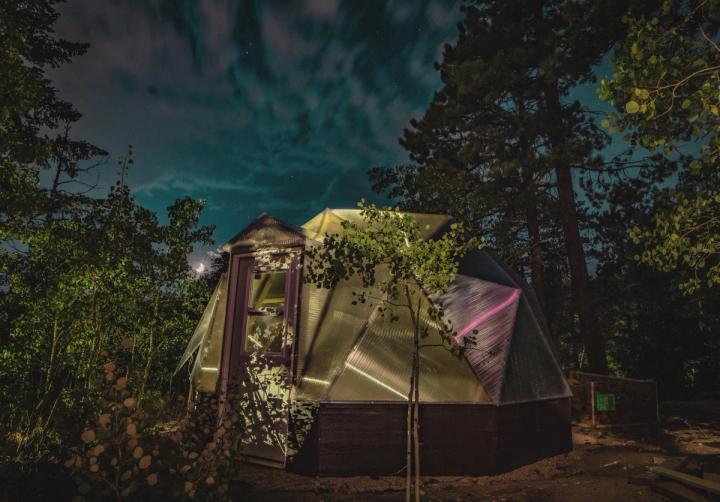 photo of a dome greenhouse at night with light reflecting off the polycarbonate