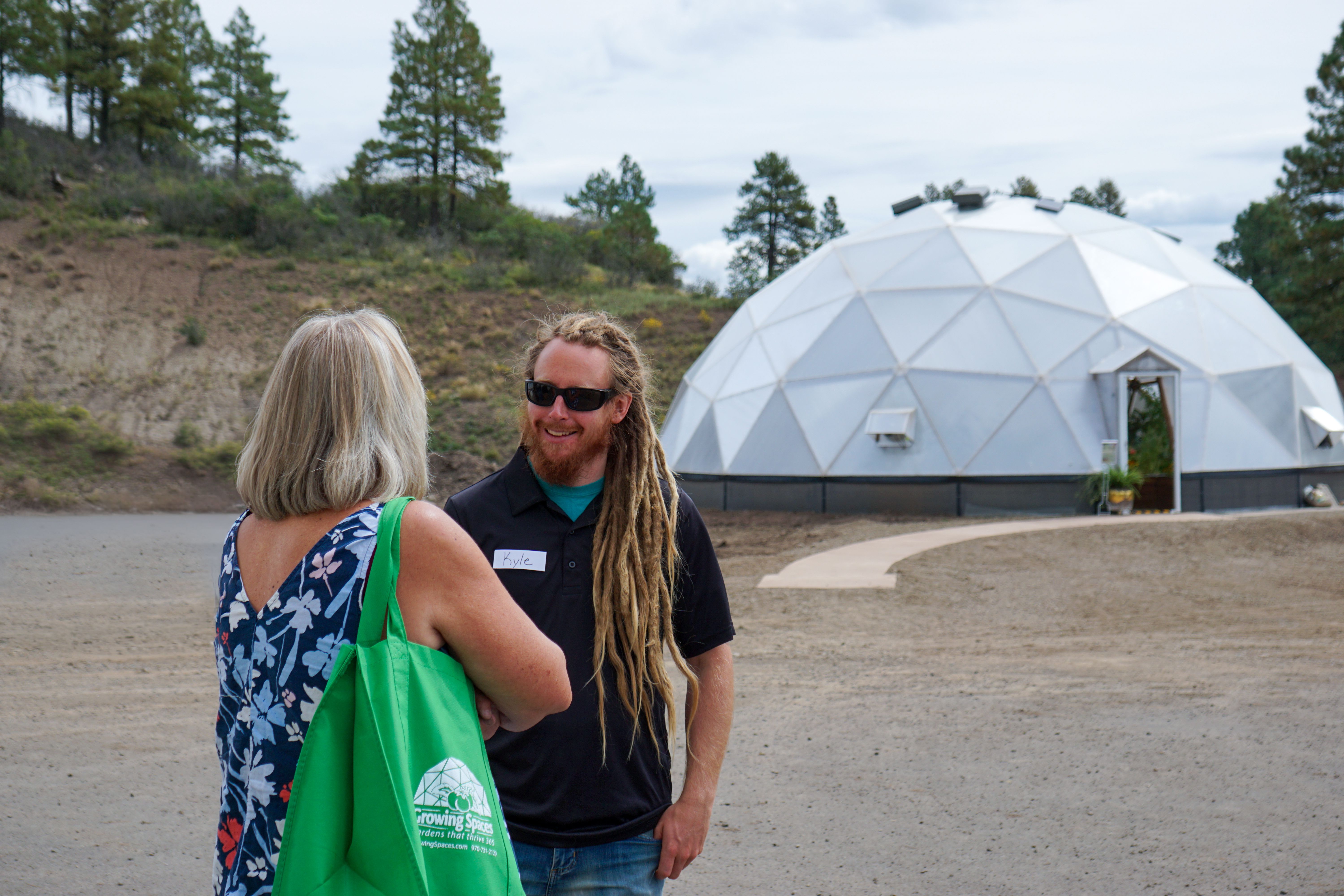 two people talking in front of a 42' Growing Dome greenhouse