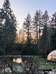 Growing Dome greenhouse in a forest setting with a light dusting of snow on the ground