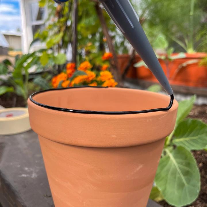Waterproof silicone being placed on the top lip of an unglazed terracotta pot.