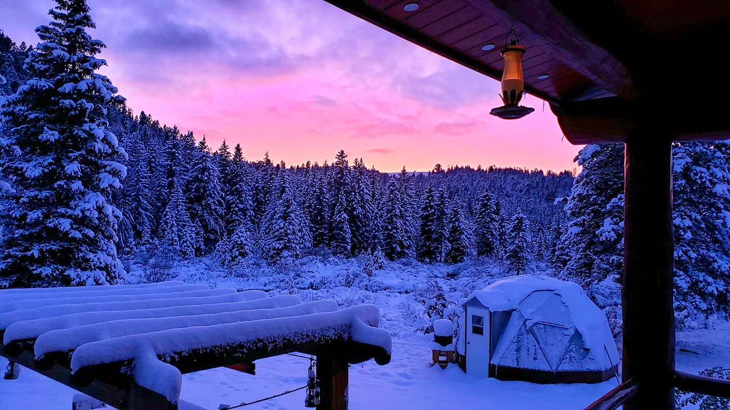 15 foot diameter geodesic greenhouse under a blanket of snow with a vibrant pink and purple sunset